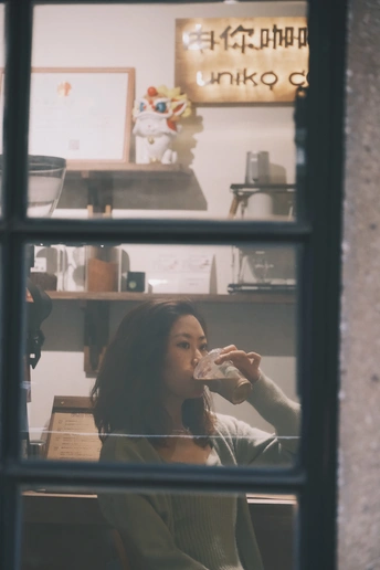 一个年轻女子坐在厨房后面 身后有玻璃和食物。