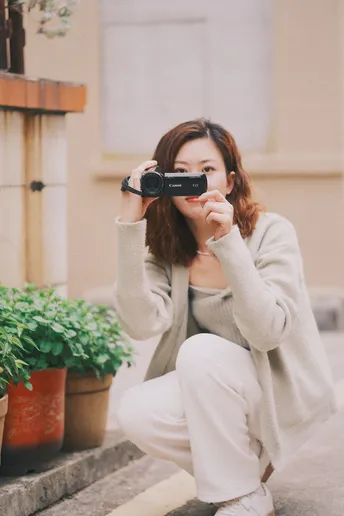 一位年轻女子在台阶上用相机拍照