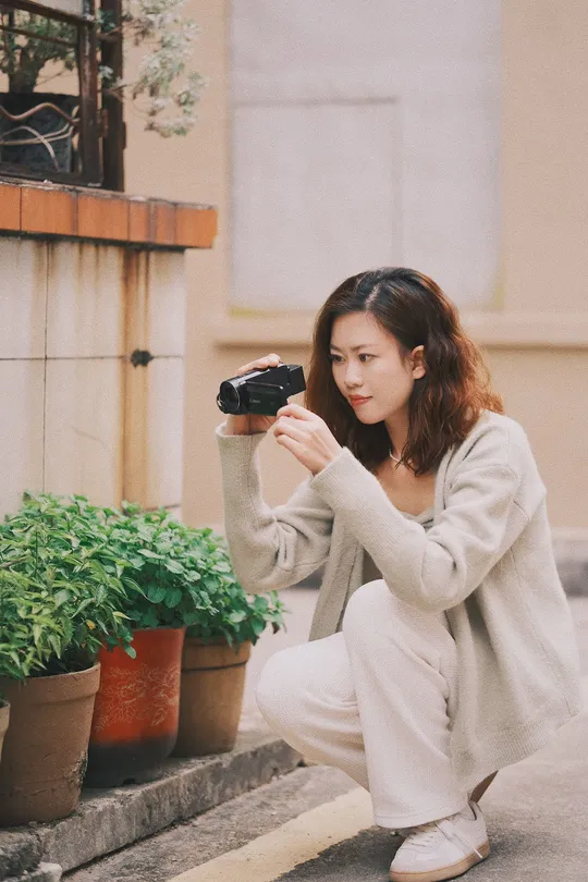 一位跪在植物前的台阶上的女性手持相机