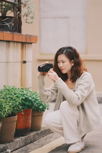 一位跪在植物前的台阶上的女性手持相机
