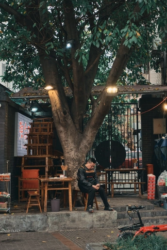 一个人坐在街边一棵大树下的小桌子上