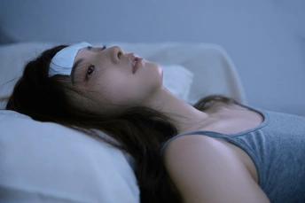 一个年轻女子躺在床上 头枕着白色枕头