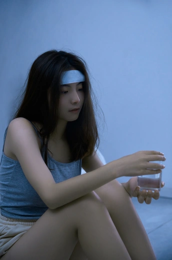 一个蓝眼睛的年轻女子坐在一个蓝色的房间里 手里拿着一杯水。