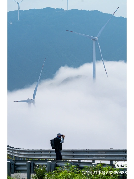 一个人正在拍摄一个风力发电厂 风力发电机在雾中矗立。