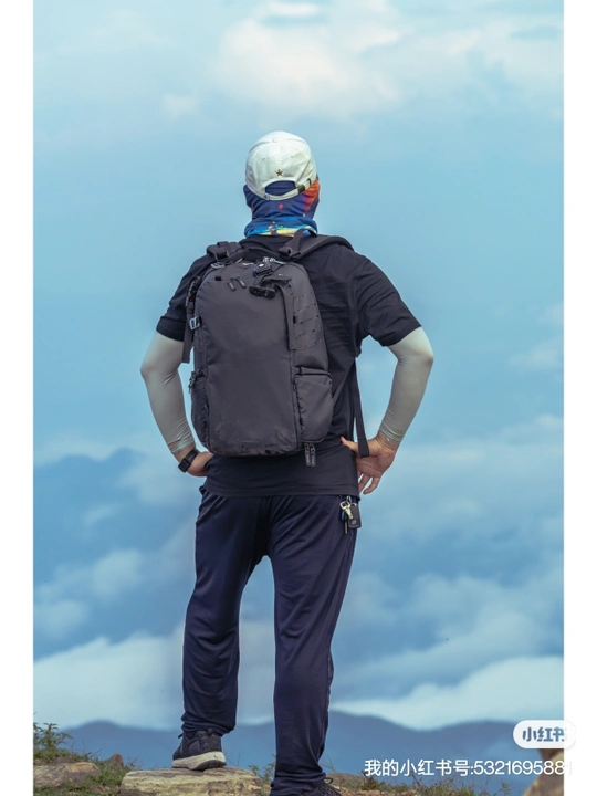 一个人背着背包站在山顶的一块岩石上
