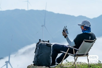 一个坐在山顶椅子上的男人 背景是风车和山脉。