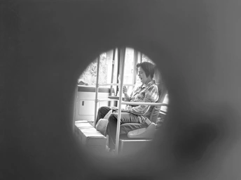 一个小女孩坐在窗台上 透过一个圆形的小孔看着里面的小男孩。