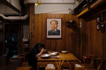一个带有木制护壁的小房间 墙上挂着一张男子坐在桌子前 桌子上放着一罐食物的肖像画。