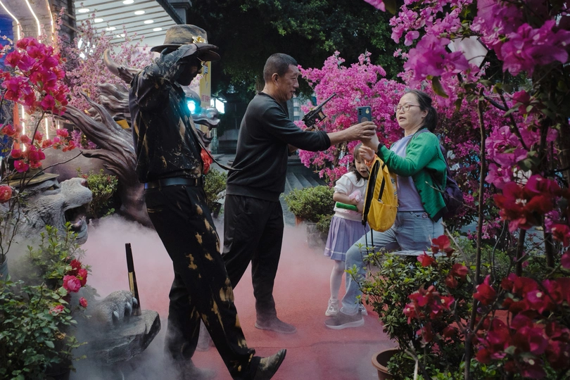 站在一位女士旁边 靠近一个花坛。