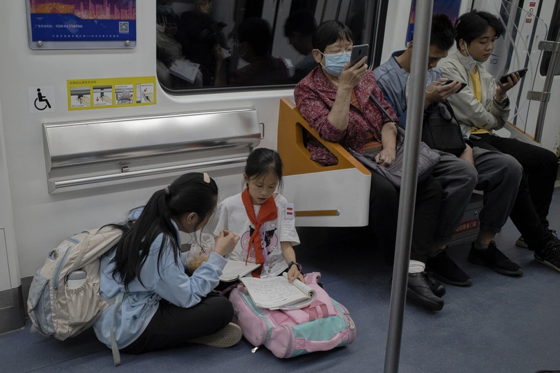 戴防护口罩的女人坐在地铁列车地板上 其他戴口罩的人坐在地铁上。