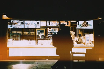 一个夜晚的黑暗房间 一个人坐在长凳上 一个人站在窗户前。