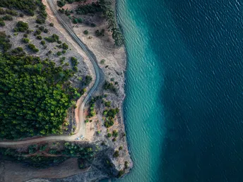 环绕着蓝色水域的湖泊或海洋中的岛屿上的公路 aerial
