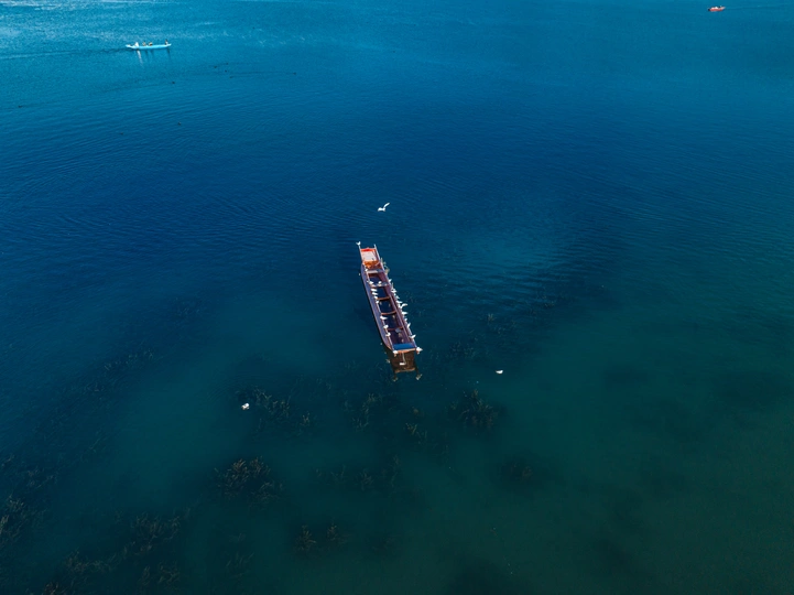 一大片蓝色水域中有一艘小船漂浮在其中。