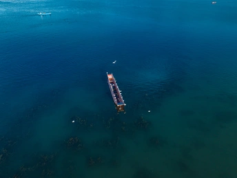 一大片蓝色水域中有一艘小船漂浮在其中。