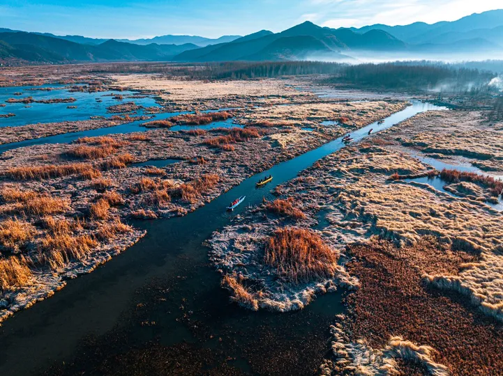 远处的山脉间流淌着一条小溪 前景中有一个冻结的沼泽地。
