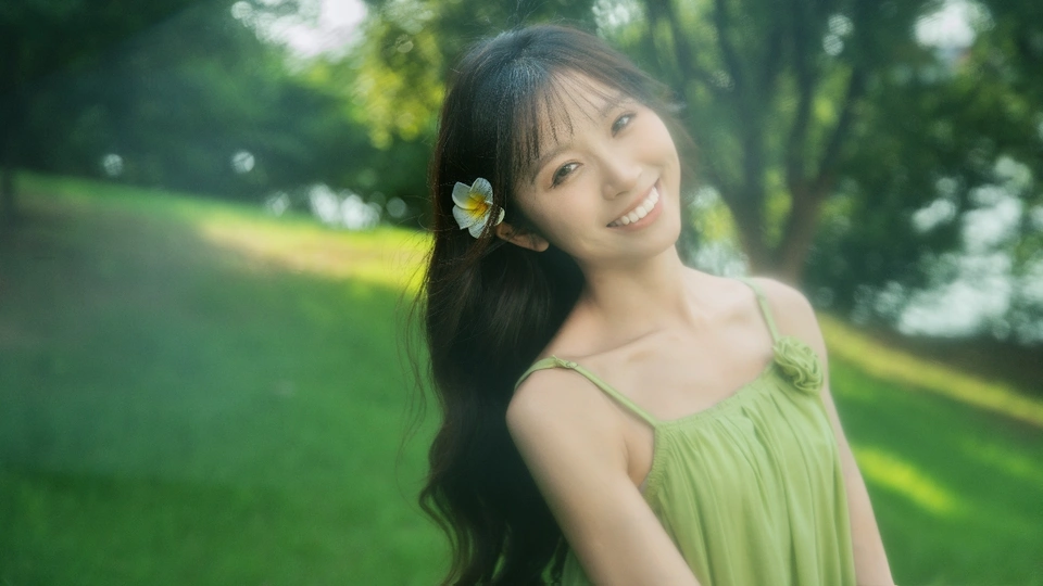 一位穿着绿色连衣裙的年轻女子站在公园里 头戴一朵花。