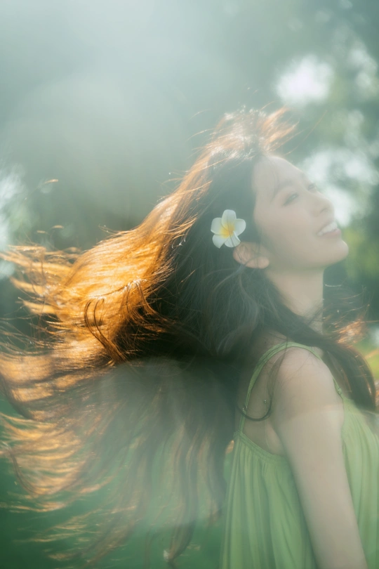 美丽的年轻女子穿着绿色裙子 头戴花 在风中吹拂。