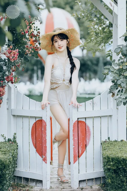 一位戴帽子的美女站在靠近白色围墙的桥上