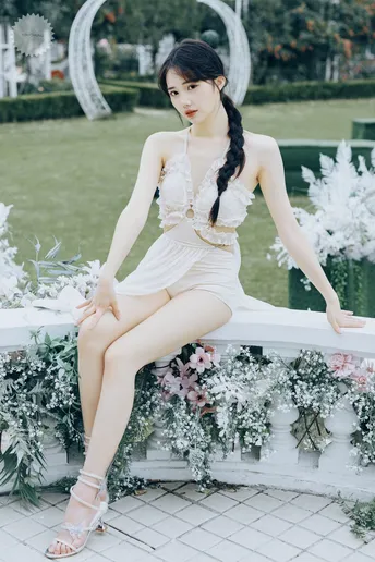 一个穿着白色裙子的女人坐在花上