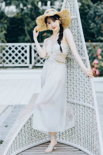 一位穿白色连衣裙和帽子站在桥上的女人