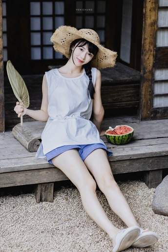 一个穿着连衣裙和帽子 坐在木凳上吃西瓜的年轻女子