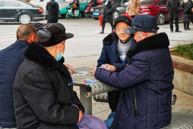 一个老人和女人在一个繁忙的街道上的一张桌子上玩纸牌。