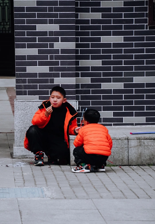 一个妇女坐在人行道上 旁边是一个坐在街上的小男孩 她正在用手机通话。