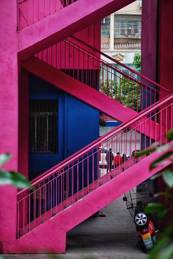 粉红色楼梯和一辆摩托车的一栋多彩建筑