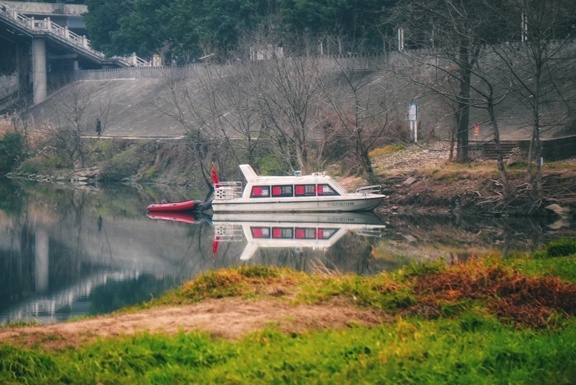 一艘白色的小船漂浮在靠近一座桥的水面上