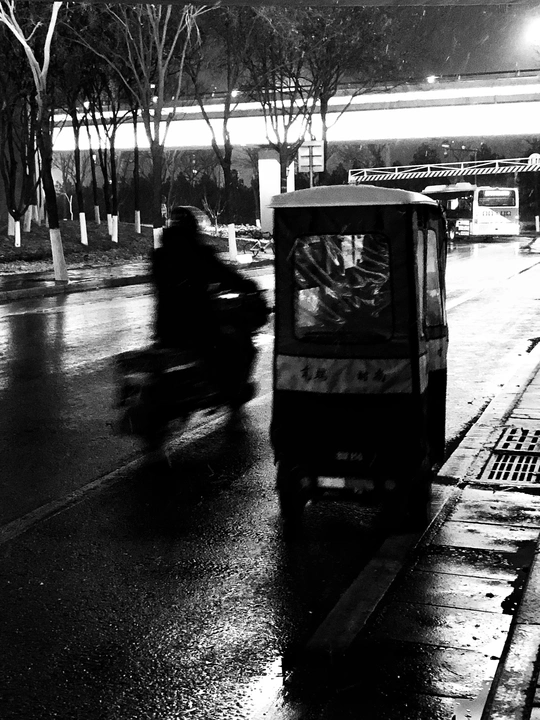 一个夜晚的雨中街道 人们骑摩托车 一辆公交车沿着湿滑的道路行驶。