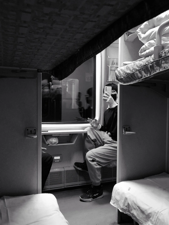 一个坐在小房间里的单人上下铺床上的男人