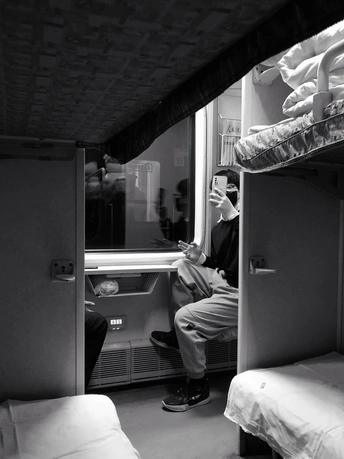 一个坐在小房间里的单人上下铺床上的男人