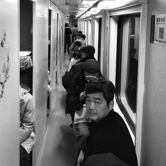 一个坐在地铁列车上的人 旁边还有其他人。