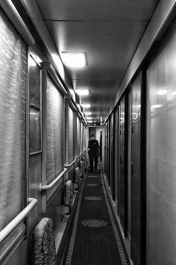 一个人在建筑物内的长走廊上行走的黑白照片