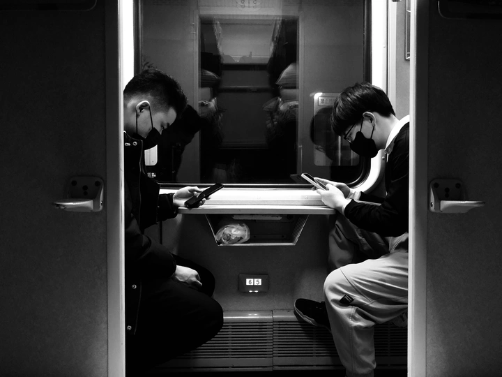 一些男人坐在地铁列车上 正在看他们的手机。