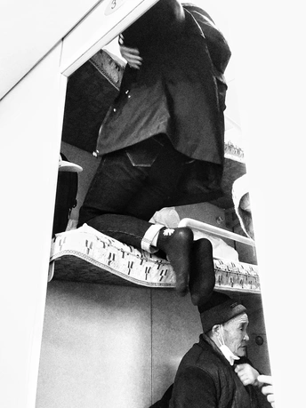 一张黑白照片 一位老人坐在墙上。