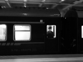 一张黑白地铁列车在车站的照片 站台上有人们 窗口里有一个男人。
