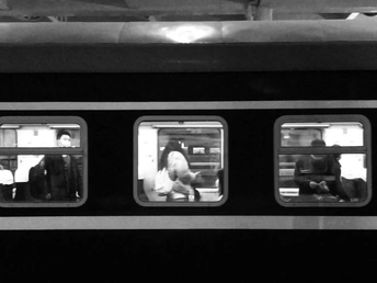 一张黑白照片 人们正在地铁列车窗口向外看。