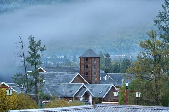 前景是一座雾气缭绕的山和一个小镇 背景中有一座教堂和其他建筑物。