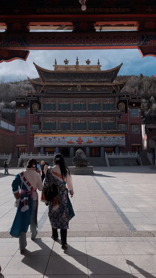 穿着和服的人们穿过一个有大门的建筑物前的庭院