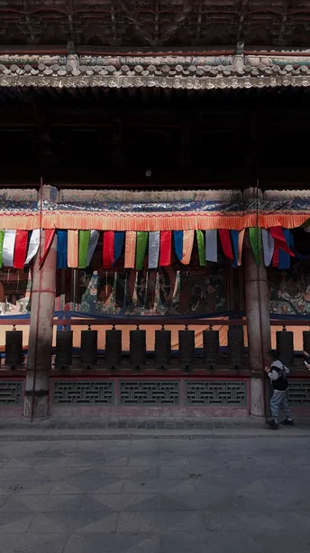 站在一栋建筑前 有一排从它上面挂下来的彩色人形线。