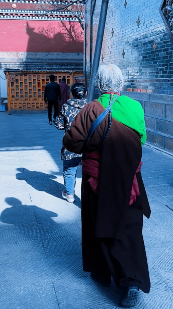 一位老妇人站在人行道上 人们路过。