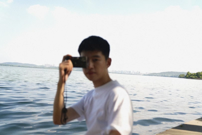 一个年轻人拿着相机在拍一艘船上的一个人。