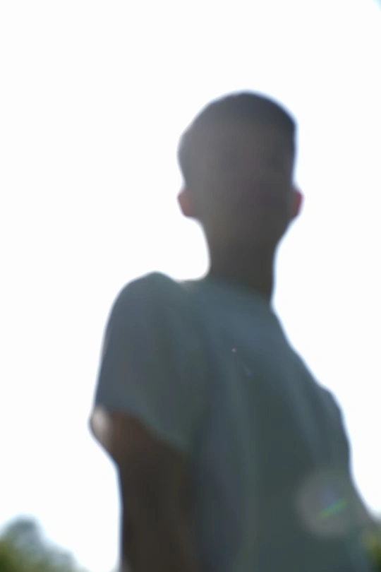 一个手里拿着飞盘的年轻人站在天上的风筝前面。