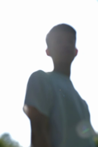 一个手里拿着飞盘的年轻人站在天上的风筝前面。