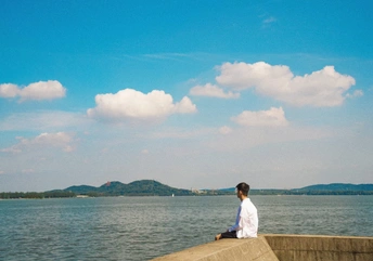 一个坐在墙上向外看水体或海洋的男子