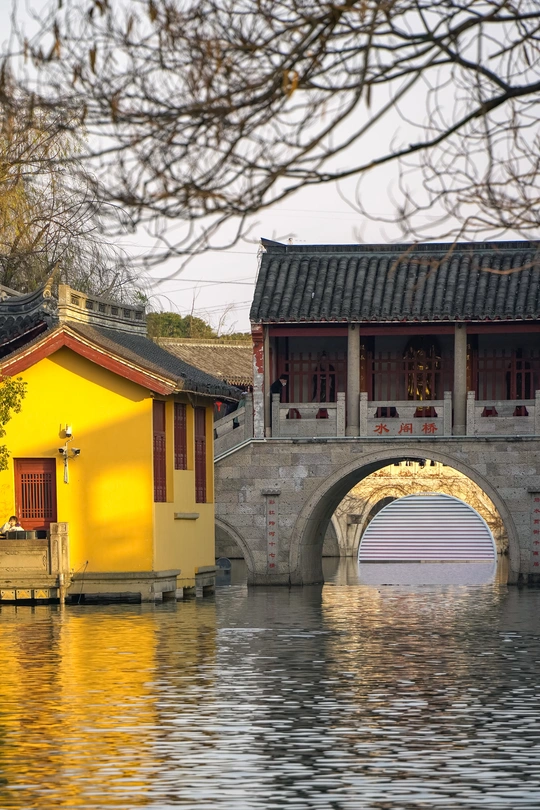 一个小水体 上方有桥 背景是一座老建筑。