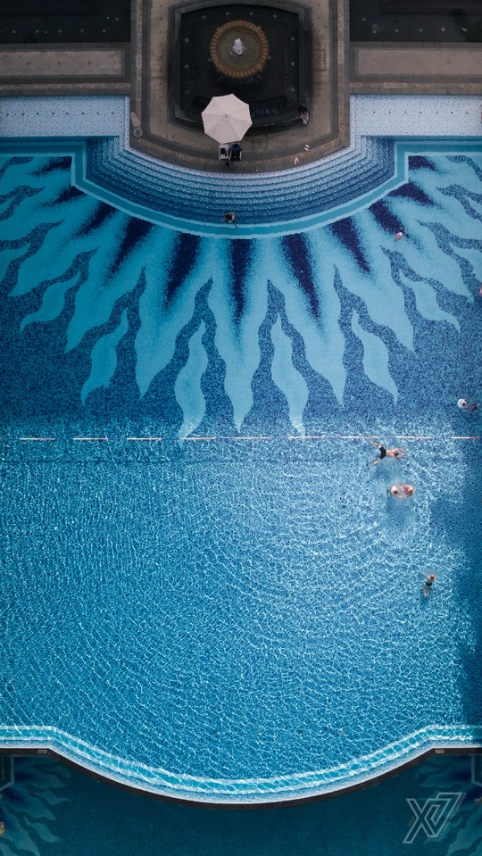 一个蓝色的游泳池 地板上有一个遮阳伞