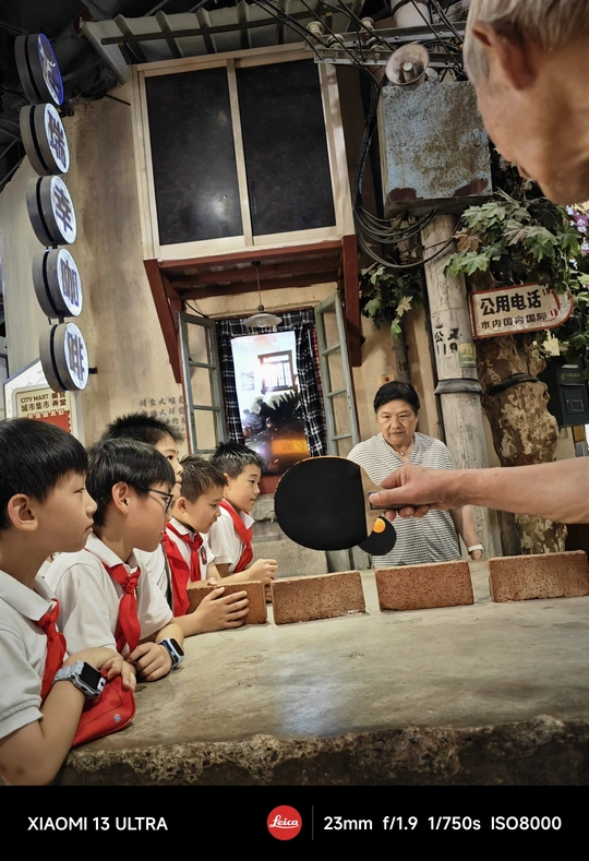 一群年轻男孩坐在桌子旁 旁边有一个拿着拍子的男人。
