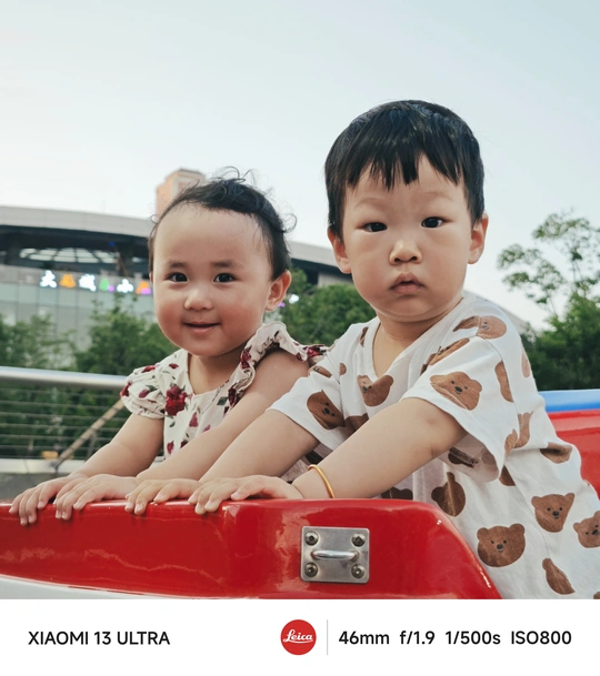 一个年轻男孩和一个小女孩骑着一辆红色的玩具车 一个小孩子坐在车顶上。